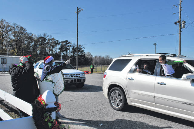 
			
				                                Deep Branch Elementary pre-kindergarten teacher Vickie Locklear waves Tuesday to kindergarten student Maddox Hunt during the school in Lumberton’s Christmas parade, as Hunt’s grandmother takes a photo.
 
			
		