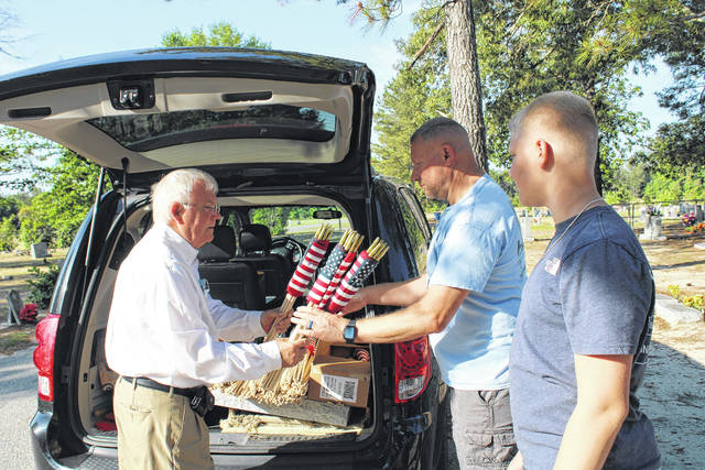 
			
				                                McNeill-Mackie Funeral Home Director Duncan Mackie hands American flags Friday to David Polega and his son Noah to be placed on the graves of fallen military men and women at Oakridge Cemetery in St. Pauls. The tradition is observed annually by the St. Pauls funeral home in honor of Memorial Day.
                                 Tomeka Sinclair | The Robesonian

			
		