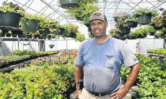 
			
				                                Ellery Locklear stands in one of his greenhouses, where flowers and flowers for baskets are grown.
                                 Photo by Les High

			
		