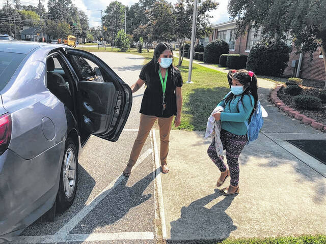 
			
				                                Nayeli Estrada, a Rowland Norment Elementary instructional assistant and intern for kindergarten classes, left, helps first-grader Aylen Baltazar to her vehicle at dismissal on Tuesday. The school has about 400 students and requires all students wear masks in accordance with the Public Schools of Robeson County’s Board of Education policy approved Tuesday.
                                 Jessica Horne | The Robesonian

			
		