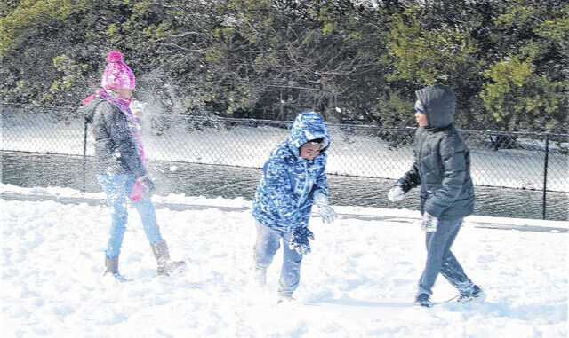 Julia Lopez, 12, left, is hit by a snowball playing with Jonathan Cousins, 9, center, and Jasiah Cousins, 12, right, in the snow Saturday on Linkhaw Road in Lumberton.
                                 Chris Stiles | The Robesonian