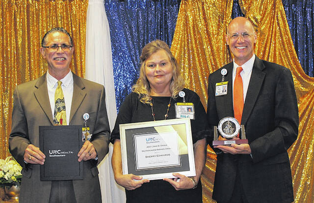 <p>UNC Health Southeastern Vice President and Chief Medical Officer Dr. Joe Roberts, left, and UNC Health Southeastern President/CEO Chris Ellington, far right, present Infection Control Manager Sherry Edwards with the 2021 John D. Drake Distinguished Service Award.</p>
                                 <p>Courtesy photos | UNC Health Southeastern</p>