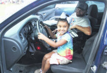 
			
				                                Lariah Hunt, 4, takes over the wheel while Officer Willie Stewart rides shotgun in this picture from 2021 at the National Night Out hosted by the Pembroke Police Department. This year’s National Night Out will take place Oct. 3 in Pembroke.
 
			
		