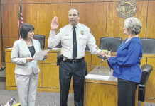 
			
				                                Interim Police Chief Adrian Hunt is installed as the new full-time police chief for the town of Pembroke on Wednesday evening. That’s Shelena Smith, the Robeson County clerk of court who administered the oath on left and Hunt’s wife, Ketisa, to the right.
                                 Michael Futch | The Robesonian

			
		