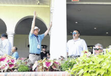 
			
				                                Dan Kenney, center, raises his hands to quiet fans on the clubhouse veranda behind the 18th green during the second round of the U.S. Open Friday in Pinehurst. Kenney is working the tournament as a volunteer in corporate hospitality.
                                 Chris Stiles | The Robesonian

			
		