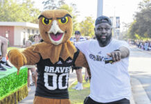 
			
				                                Lamar Courmon, right, UNCP’s assistant athletic director for creative services and broadcasting, poses for a photo with the school’s mascot, Bravehawk.
                                 Contributed photo | Lamar Courmon

			
		